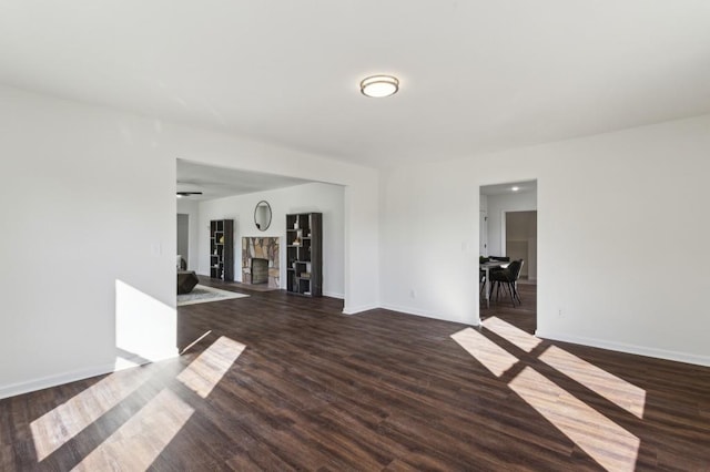 unfurnished room with a fireplace, baseboards, and wood finished floors