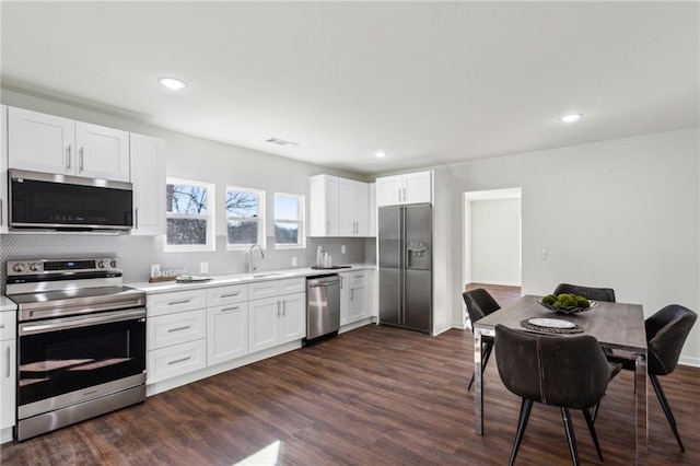 kitchen with dark wood-style floors, stainless steel appliances, light countertops, and visible vents