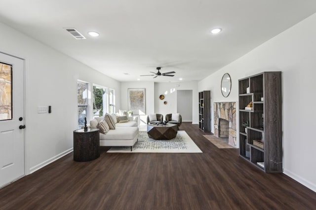 living area with a stone fireplace, recessed lighting, wood finished floors, and baseboards