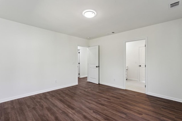 unfurnished bedroom with dark wood-style floors, visible vents, and baseboards