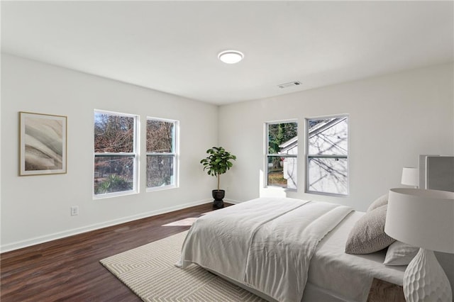 bedroom featuring baseboards, visible vents, and dark wood finished floors