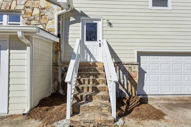 entrance to property featuring an attached garage and stone siding