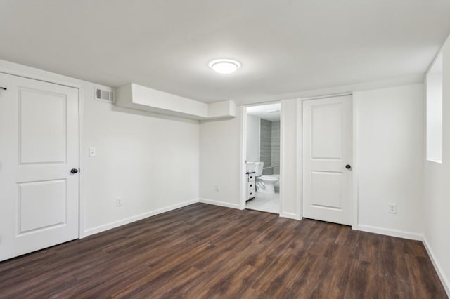 empty room with visible vents, dark wood finished floors, and baseboards