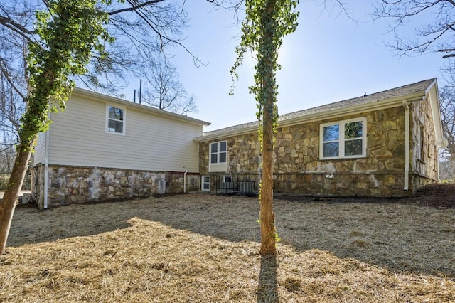 back of house with stone siding and central AC unit