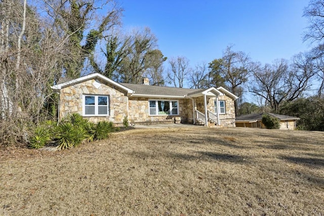 ranch-style house with stone siding, a chimney, and a front yard