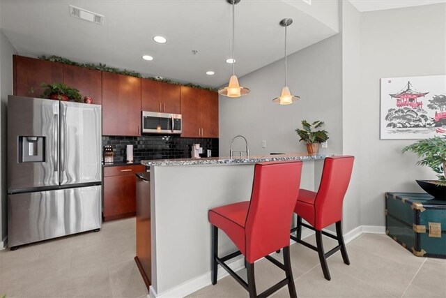 kitchen with pendant lighting, sink, stainless steel appliances, a kitchen breakfast bar, and decorative backsplash