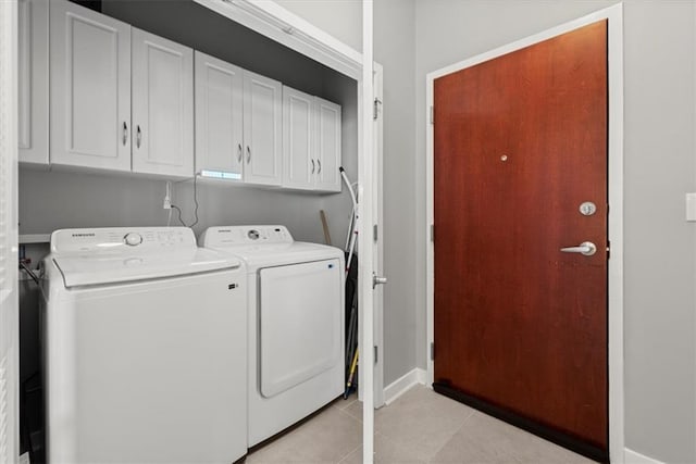 laundry room with cabinets, light tile patterned floors, and washing machine and clothes dryer