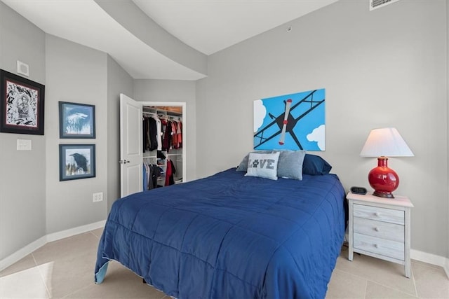 bedroom with a walk in closet, light tile patterned floors, and a closet