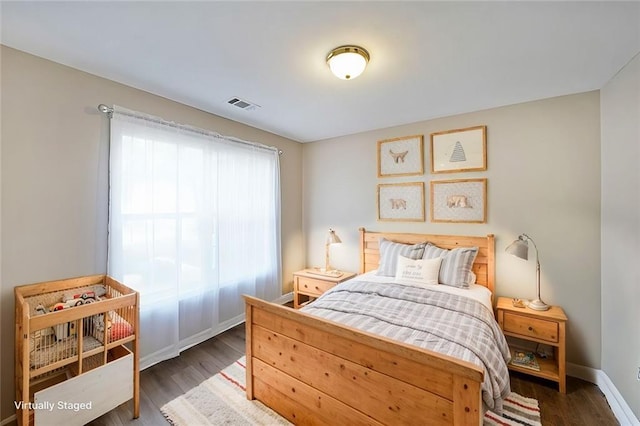 bedroom with visible vents, baseboards, and wood finished floors