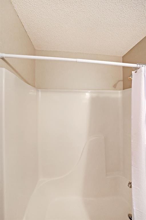 full bathroom with curtained shower and a textured ceiling