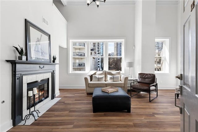 living area with a fireplace, wood finished floors, visible vents, baseboards, and crown molding