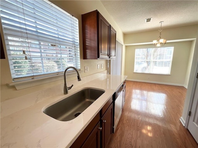 kitchen featuring a textured ceiling, a sink, visible vents, dishwasher, and pendant lighting