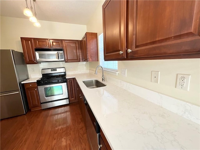 kitchen with dark wood-style floors, decorative light fixtures, stainless steel appliances, light countertops, and a sink