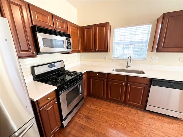 kitchen with light countertops, appliances with stainless steel finishes, light wood-type flooring, and a sink