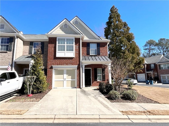 view of front of property featuring brick siding, concrete driveway, an attached garage, a standing seam roof, and metal roof