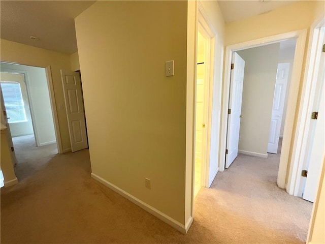 hallway with light carpet and baseboards