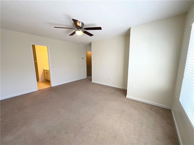 unfurnished bedroom featuring baseboards, ensuite bath, a ceiling fan, and light colored carpet