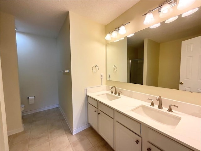 bathroom featuring double vanity, a shower stall, a sink, and tile patterned floors