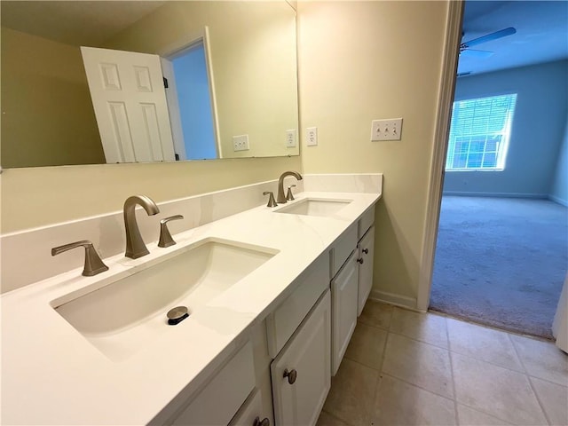 full bath with tile patterned flooring, a sink, baseboards, and double vanity