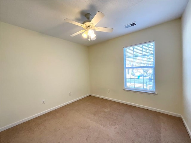 unfurnished room with light colored carpet, visible vents, ceiling fan, and baseboards