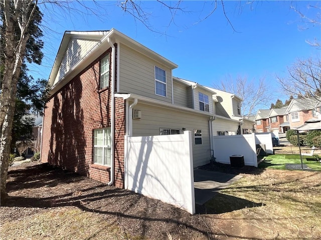 rear view of house with a garage, brick siding, fence, and a residential view