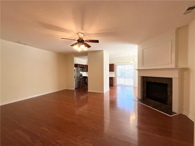 unfurnished living room with visible vents, dark wood-type flooring, a high end fireplace, a ceiling fan, and baseboards