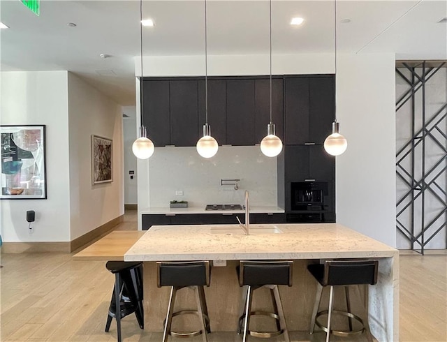 788 W Marietta St NW Unit 512, Atlanta, GA 30318 - kitchen featuring dark cabinets, modern cabinets, light wood-type flooring, a center island with sink, and pendant lighting