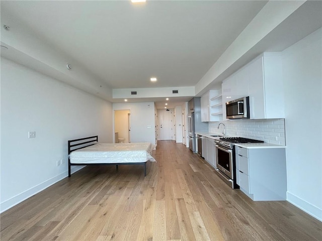 788 W Marietta St NW Unit 512, Atlanta, GA 30318 - kitchen with high quality appliances, white cabinets, light wood-style flooring, tasteful backsplash, and light countertops
