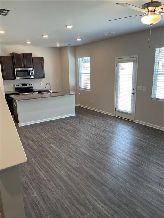 kitchen with appliances with stainless steel finishes, dark hardwood / wood-style flooring, a kitchen island with sink, and sink