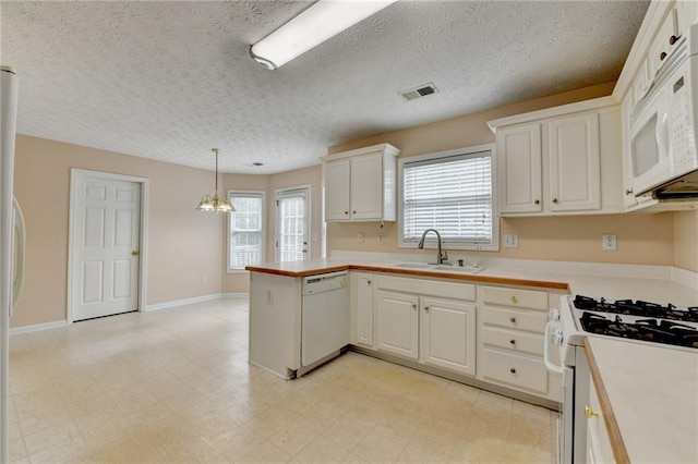 kitchen with a sink, white appliances, light countertops, white cabinets, and a peninsula