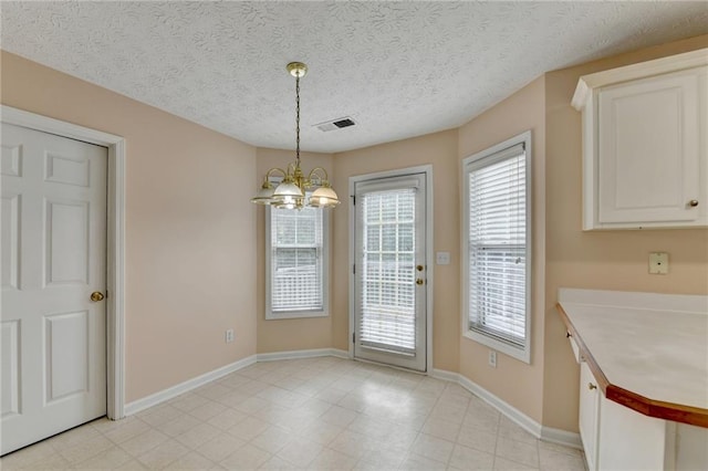 unfurnished dining area featuring a chandelier, baseboards, and a textured ceiling