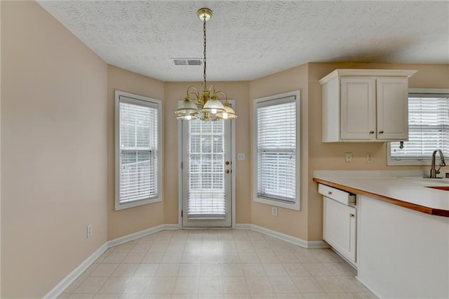 unfurnished dining area featuring a chandelier, baseboards, a textured ceiling, and a sink