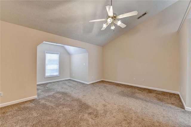 additional living space featuring lofted ceiling, carpet flooring, a ceiling fan, baseboards, and a textured ceiling
