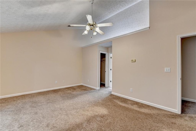 unfurnished room with carpet floors, a ceiling fan, vaulted ceiling, baseboards, and a textured ceiling