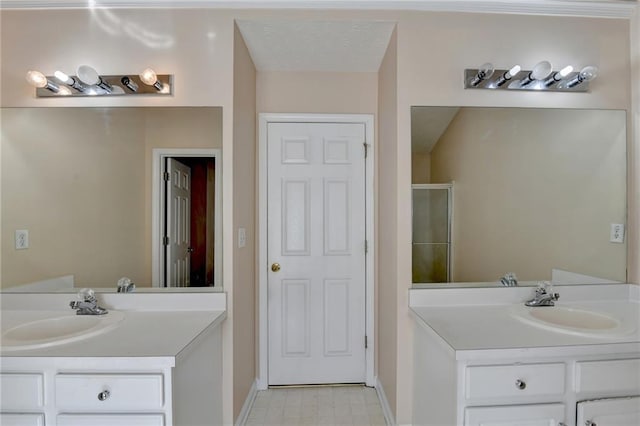 full bath featuring a stall shower, tile patterned floors, two vanities, and baseboards