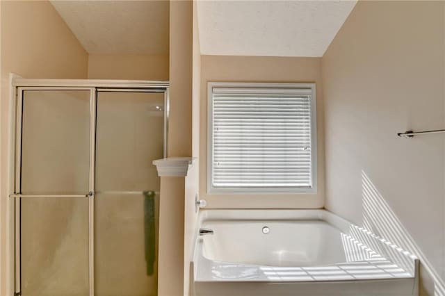 full bath featuring a shower stall, a bath, and a textured ceiling