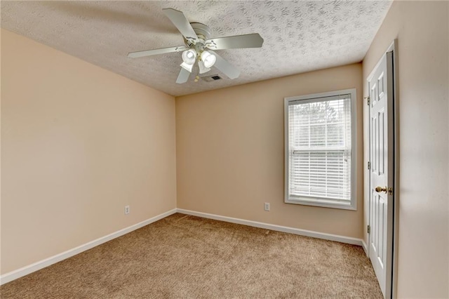 empty room featuring light carpet, a textured ceiling, ceiling fan, and baseboards