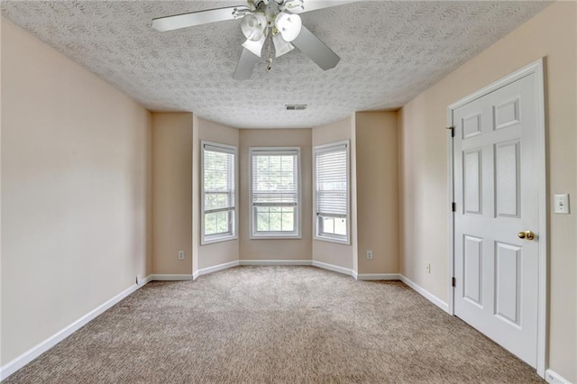 unfurnished room featuring a ceiling fan, carpet, a textured ceiling, and baseboards