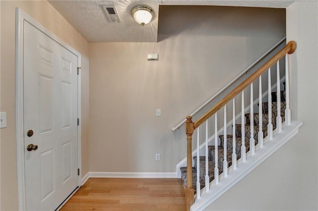entryway with wood finished floors, stairs, baseboards, and a textured ceiling