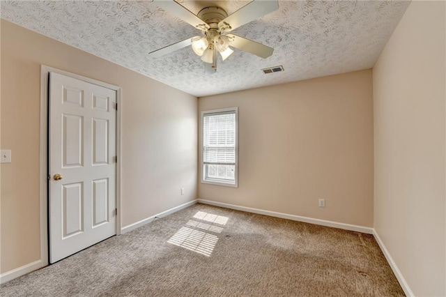 empty room with carpet floors, a textured ceiling, baseboards, and a ceiling fan