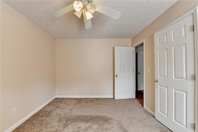unfurnished bedroom featuring light carpet, baseboards, a textured ceiling, and ceiling fan