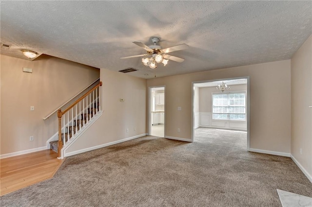 unfurnished room featuring ceiling fan, stairs, a textured ceiling, carpet, and a chandelier