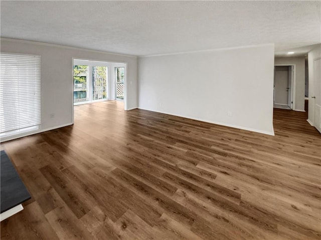 empty room with dark hardwood / wood-style floors, ornamental molding, and a textured ceiling