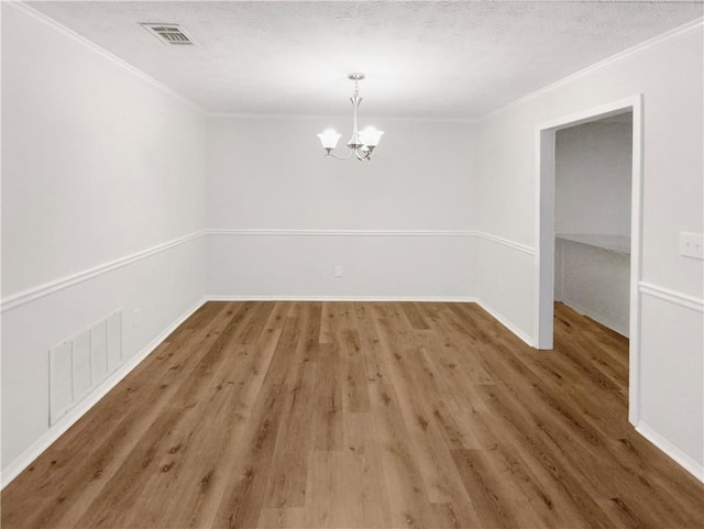 unfurnished dining area with a chandelier, hardwood / wood-style floors, a textured ceiling, and crown molding