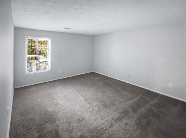 unfurnished room featuring dark carpet