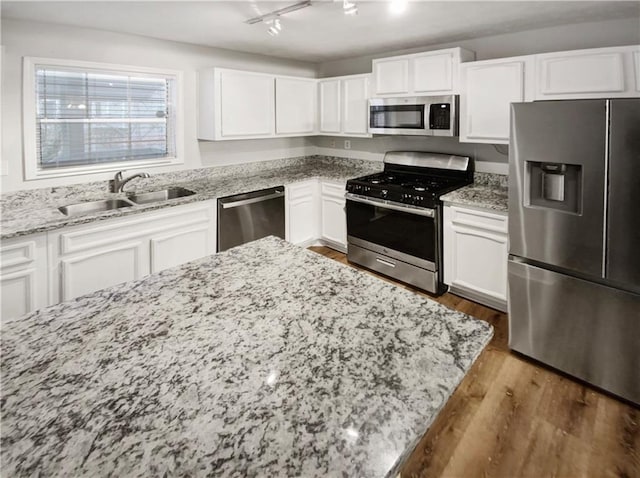 kitchen with sink, white cabinets, stainless steel appliances, and wood-type flooring