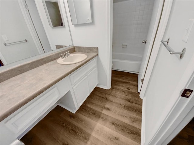 full bathroom with tiled shower / bath, toilet, vanity, and hardwood / wood-style flooring