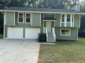 split foyer home featuring a garage, concrete driveway, and a front yard