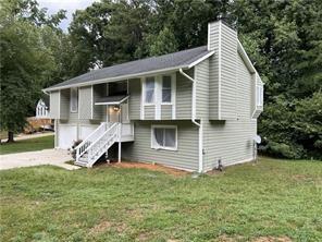 split foyer home with a garage, a chimney, concrete driveway, and a front lawn