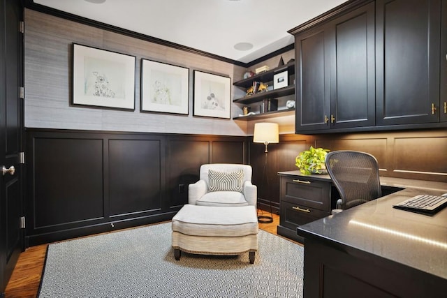 office area with built in desk, light wood-type flooring, and ornamental molding